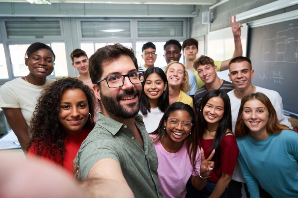 Smiling teacher taking a selfie with a diverse group of happy students in a classroom at ILC Hua Hin