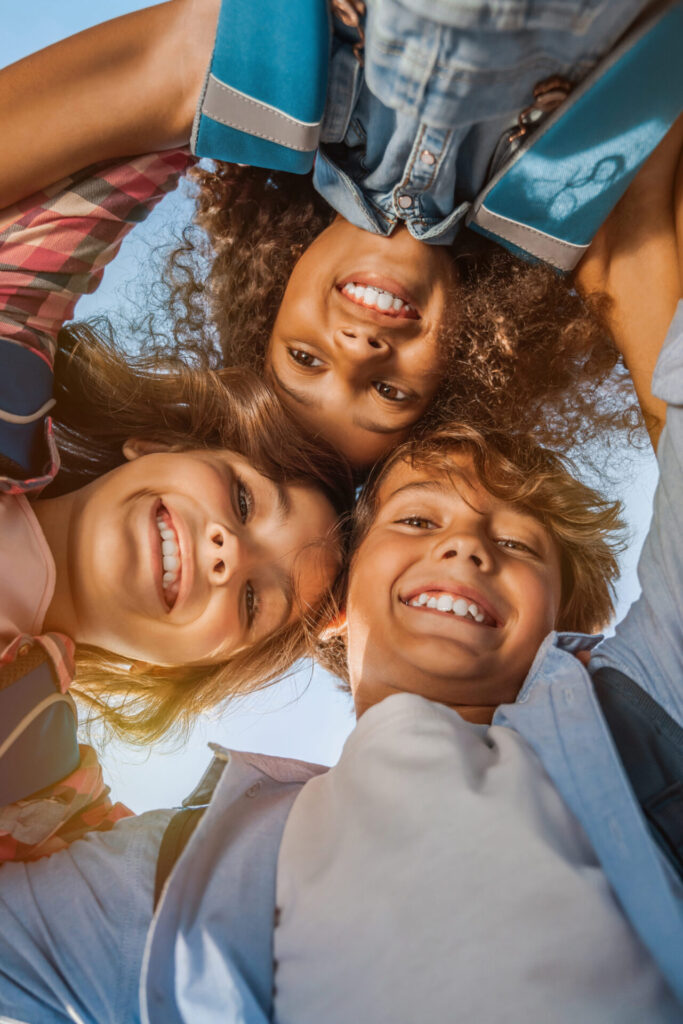 Happy children lying in a circle outdoors, smiling and laughing together – Holiday English Club for Kids in Hua Hin, Thailand