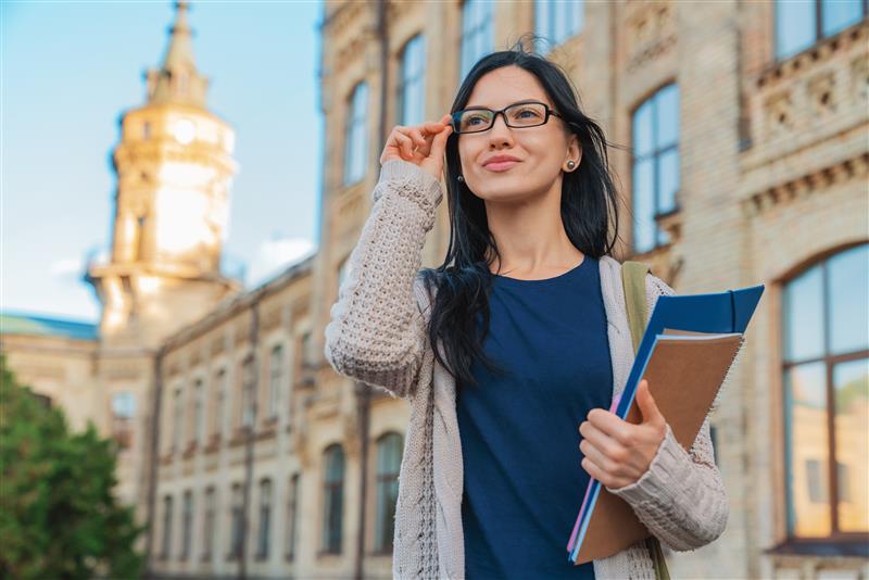 IELTS One-to-One Coaching student outside university building holding books and smiling