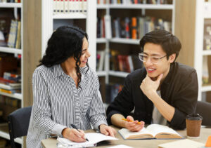 นักเรียนสองคนเรียนด้วยกันในห้องสมุดเพื่อโพสต์บล็อกการเรียนรู้ภาษาอังกฤษ