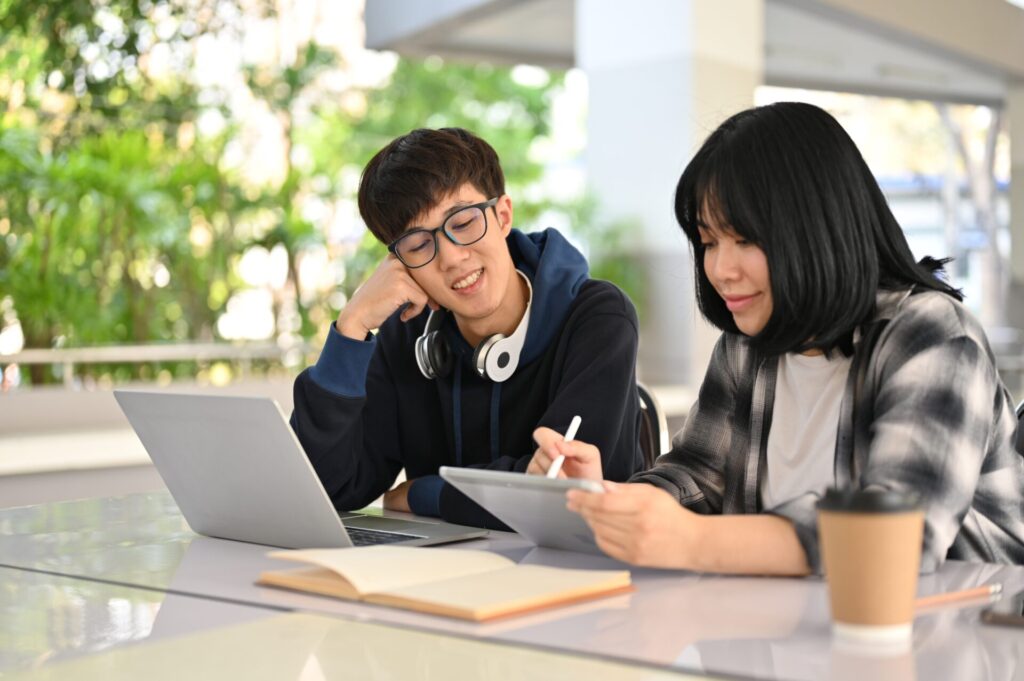 Two students studying together with a laptop and tablet during IELTS One Skill Boost preparation at ILC Training.