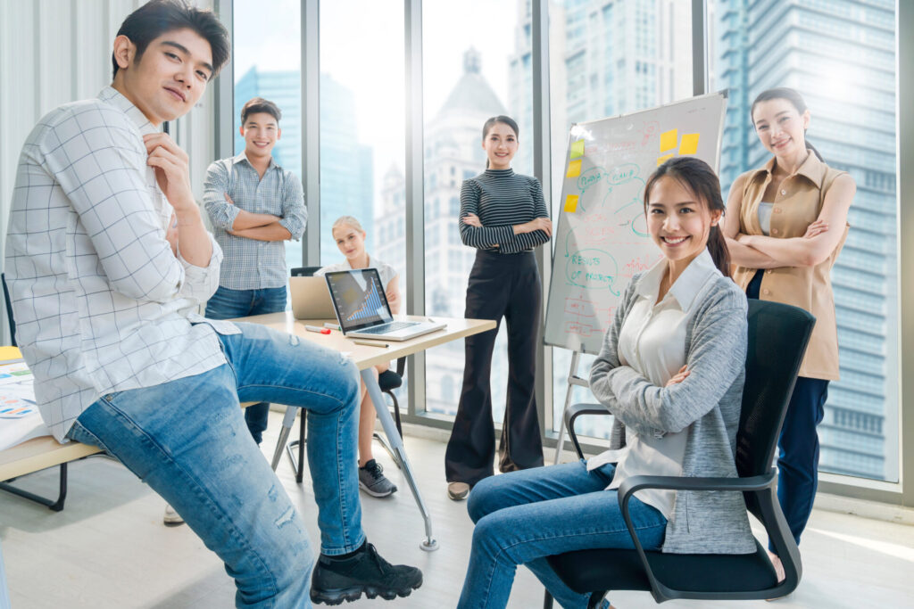 Group of young professionals in a modern office preparing for IELTS Work and Careers 2025 theme, smiling confidently as part of exam preparation.