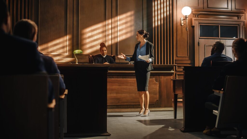 Lawyer speaking in courtroom with judge and jury, representing justice, legal process, and punishment for IELTS Crime and Punishment topics.