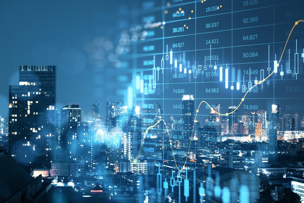 City skyline at night with digital stock market charts and rising financial data, symbolising IELTS Economy and Trade, global markets, and consumerism.