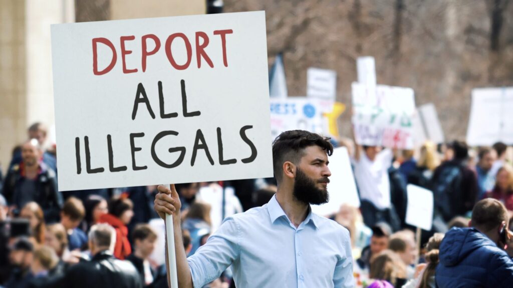 IELTS Migration and Immigration 2025 – protest with sign about immigration policies