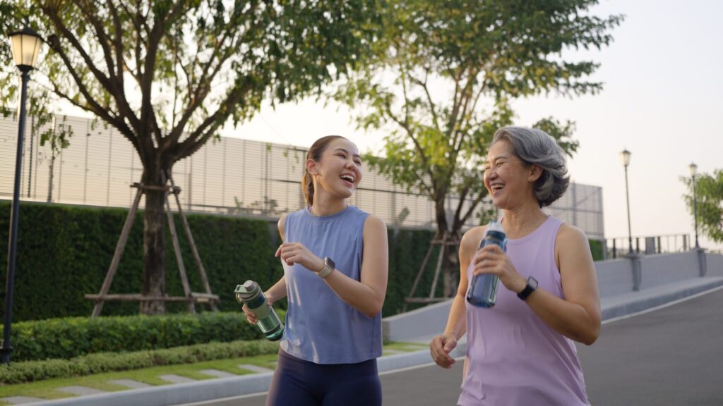 Two women jogging outdoors with water bottles, symbolising IELTS Health & Wellbeing preparation 2025