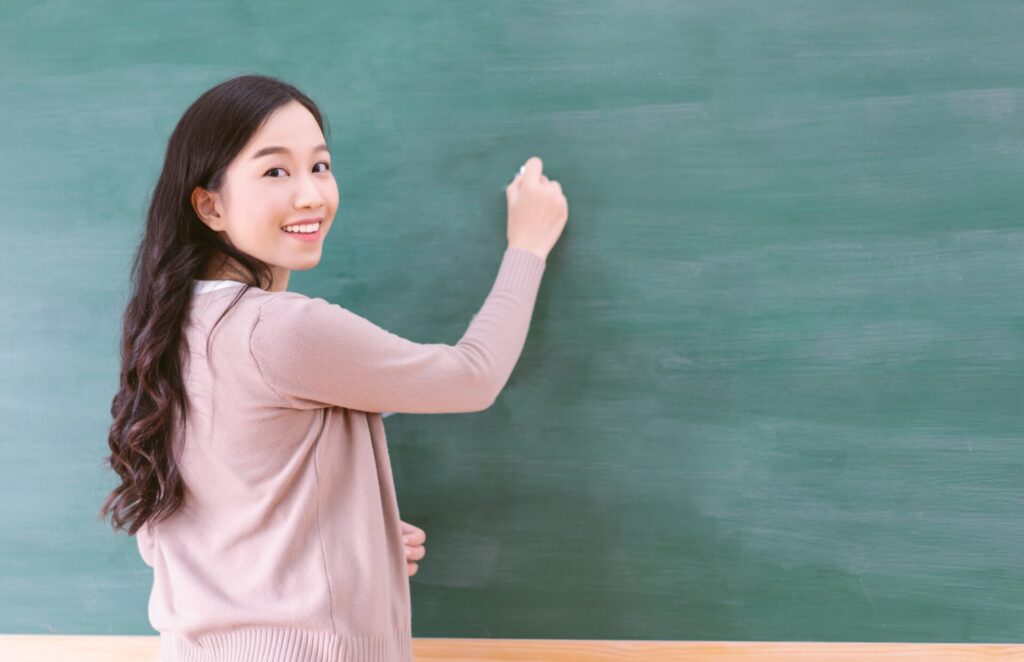 English teacher smiling at the board at ILC Hua Hin – Learn English in Hua Hin