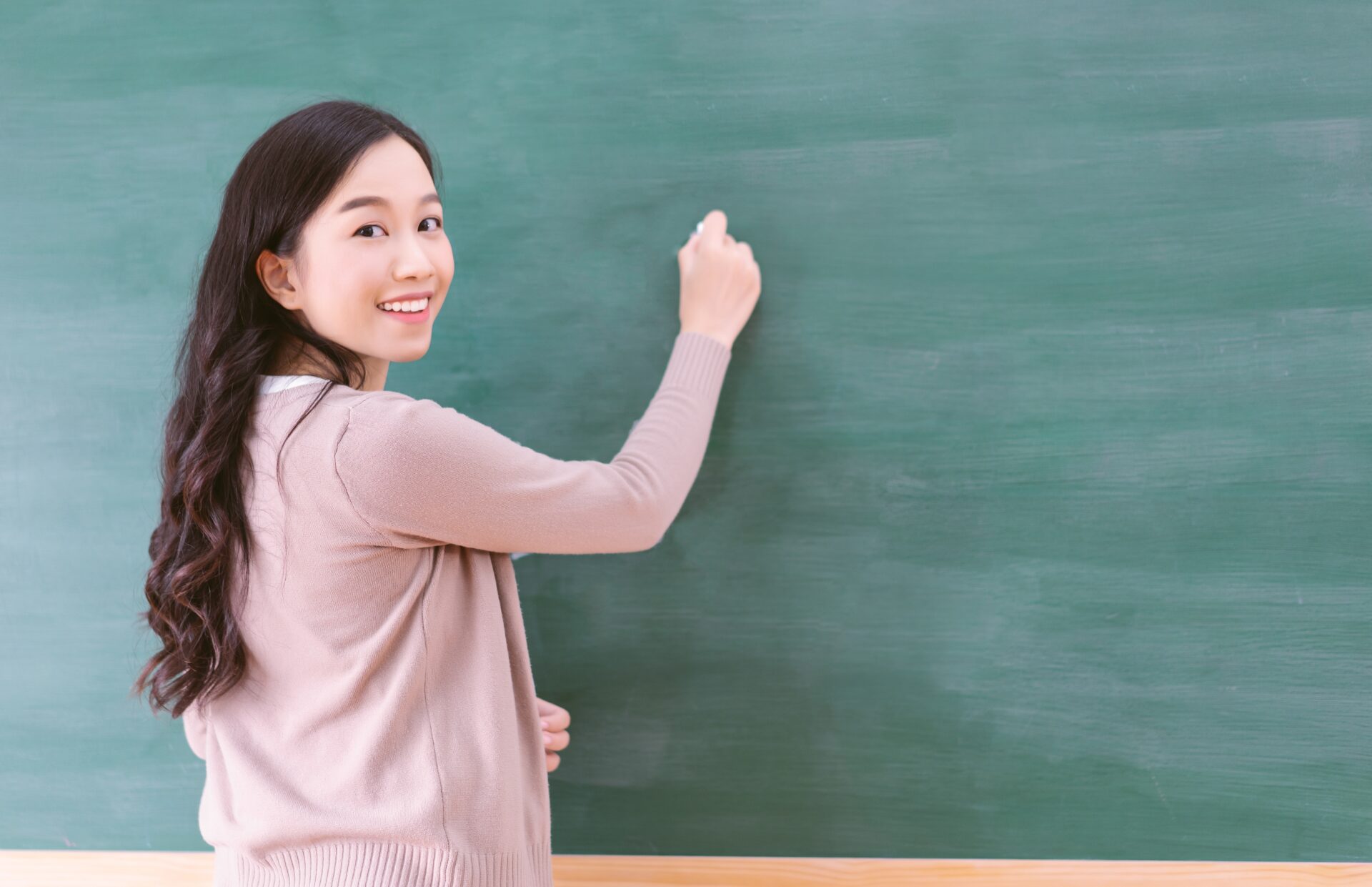 English teacher smiling at the board at ILC Hua Hin – Learn English in Hua Hin