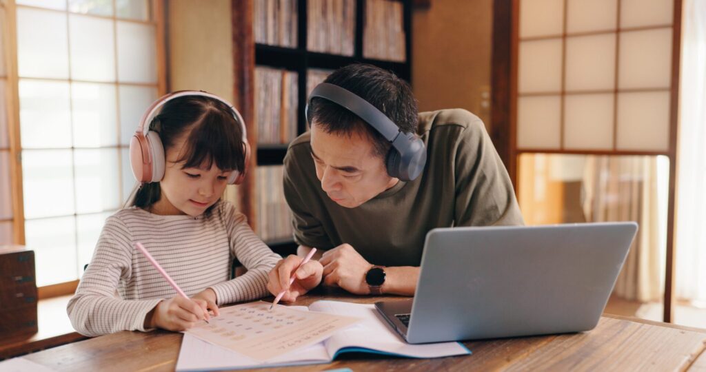 Father helping daughter study English at home during an online lesson – Learn English for Beginners in Thailand