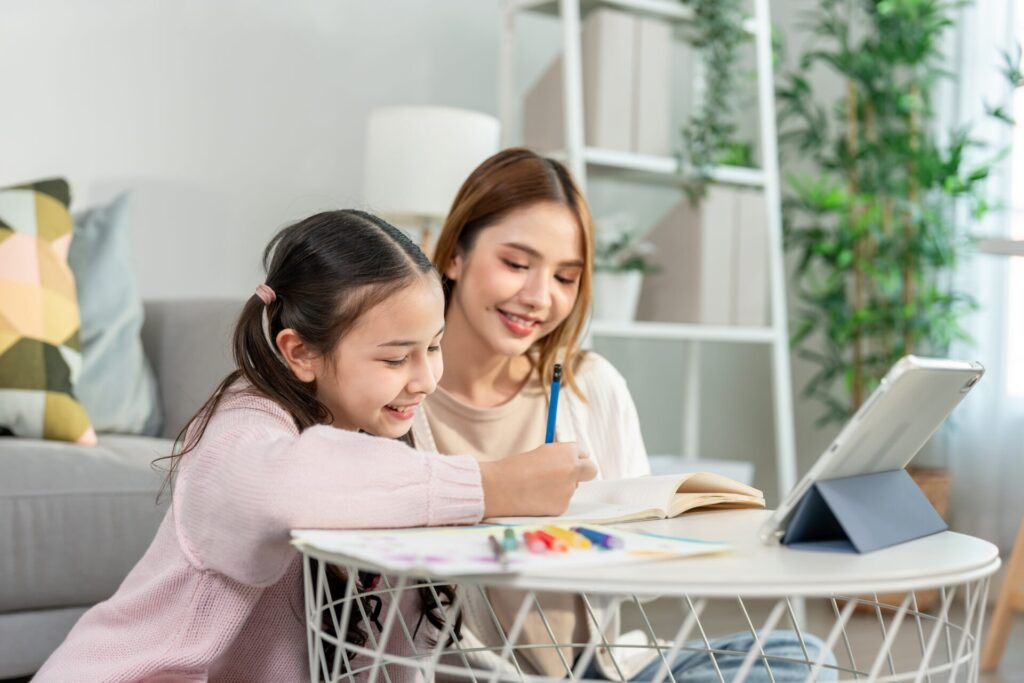 A smiling English coach helping a young student learn online at ILC Hua Hin during an English in Hua Hin beginner course.
