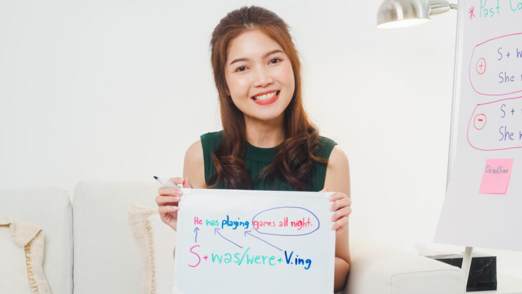 Adult English Classes 3 Smiling English teacher holding a whiteboard while explaining grammar during adult english classes at ILC Hua Hin.