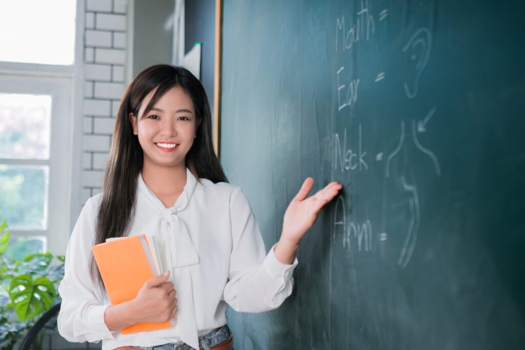Teacher pointing at the board while helping a student understand English vocabulary to support student progress.