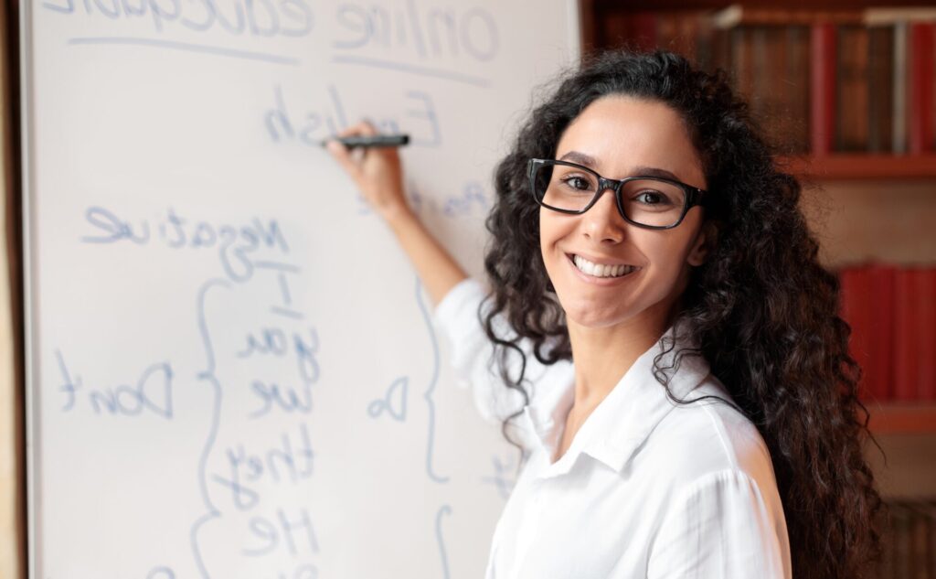 Adult English Classes: The Ultimate Guide to Reinforcement 3 Teacher smiling while teaching Adult English Classes at a whiteboard