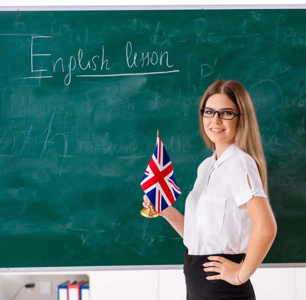 Beginner English lesson with female instructor holding UK flag in classroom